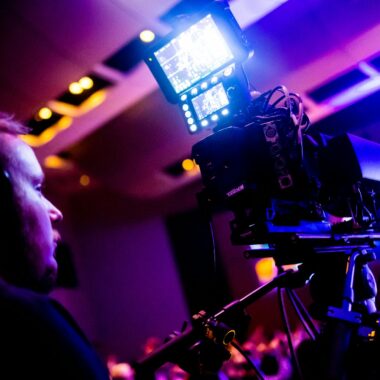 A professional cameraman operating a camera during a vibrant nightlife event indoors.