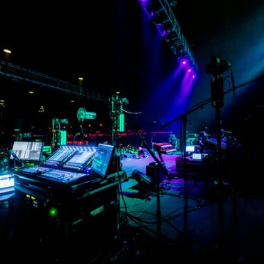 Energetic concert scene with illuminated stage and sound equipment.