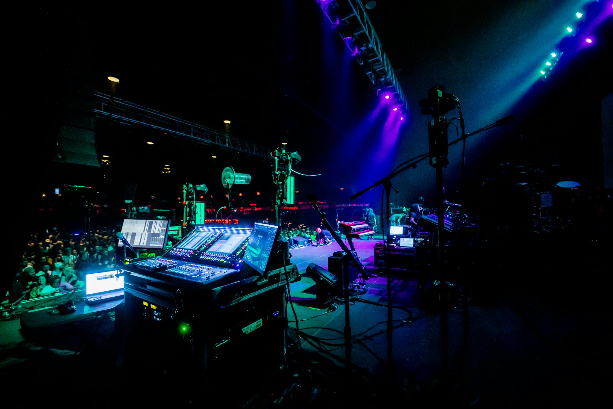 Energetic concert scene with illuminated stage and sound equipment.